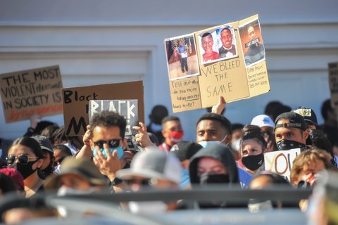 Protesters in masks carrying signs