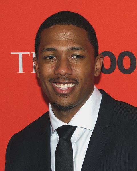 Nick Cannon in suit and tie against red backdrop