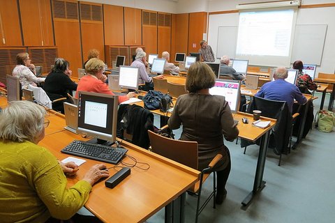 View from behind of older adults at computers in a class.