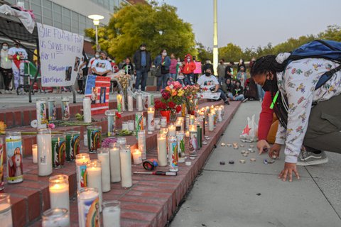 Person in mask kneels next to steps lined with candles