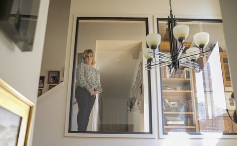 Reflection of woman in mirror next to hanging light fixture