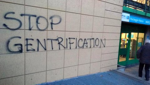 Wall with graffiti that reads "stop gentrification."