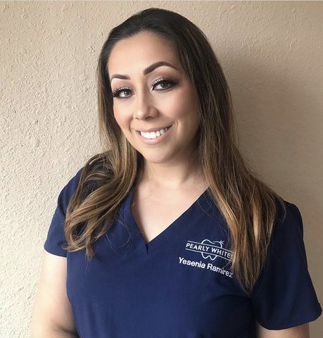 Smiling Latina woman in dark blue scrub top that says "Pearly Whites Yesenia Ramirez" with tooth logo.