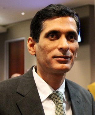 An Indian man in a dark suit and patterned tie