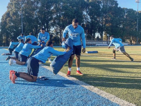 Football players and coaches during a practice drill