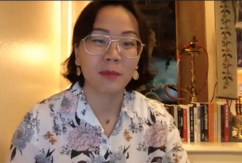 Asian woman wearing glasses with books behind her