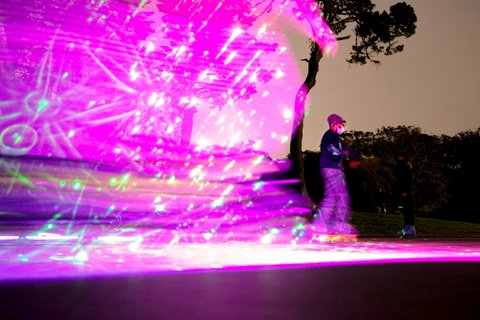 Roller skater with pink light display trailing behind them