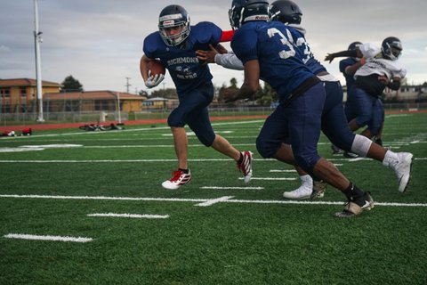Football player runs with ball held to his side