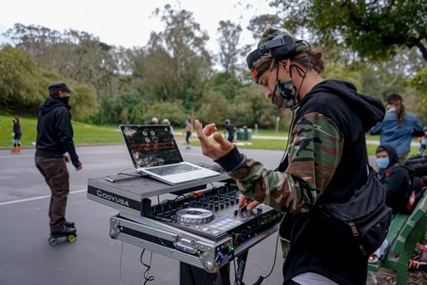 Reverse view from the side of a DJ at his turntable in Golden Gate Park
