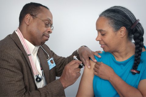 Black man gives vaccine shot in Black woman's arm