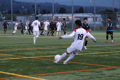 Player in white no. 19 jersey kicks the ball during a soccer game.