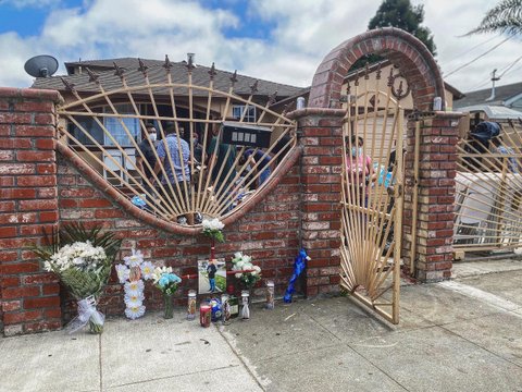 Vigil in front of a brick wall and fence in front of a house