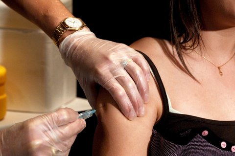 Closeup of a young woman receiving a shot in her arm