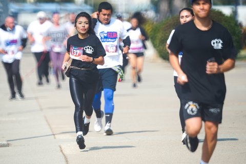 A group of runners with a young Latina in sharper focus than the rest