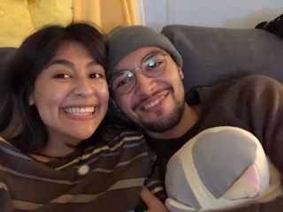 A young woman and man, smiling side by side on a sofa