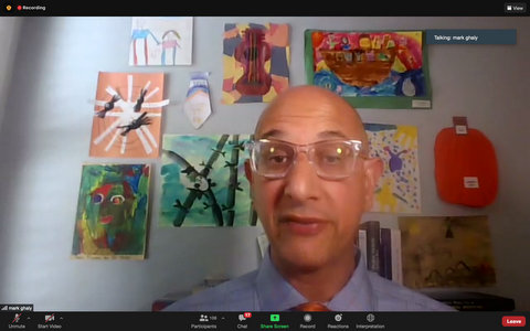 Bald man with glasses in front of wall with children's artwork
