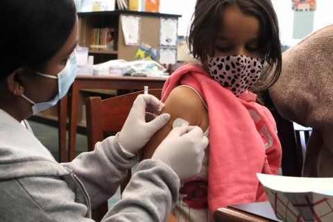 A medical worker applies a bandage to a little girl's arm after giving her a shot.