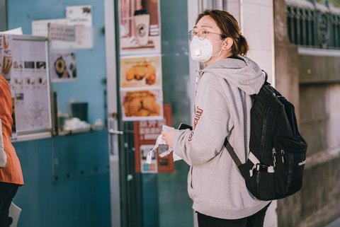 Young Asian woman wearing glasses, a mask and a backpack