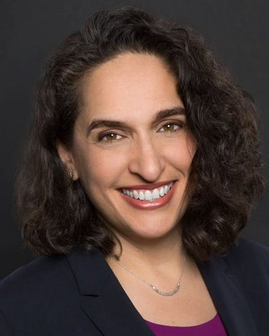 A smiling white woman with curly, brown hair.