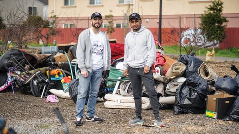 Two young Latino men standing in front of collected trash