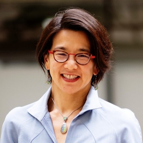 A smiling Asian woman with glasses, short hair and a blue top