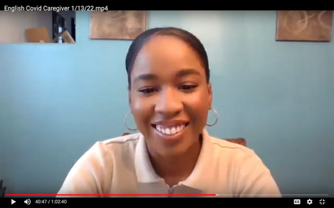 A smiling young Black woman who is wearing a polo shirt and hoop earrings