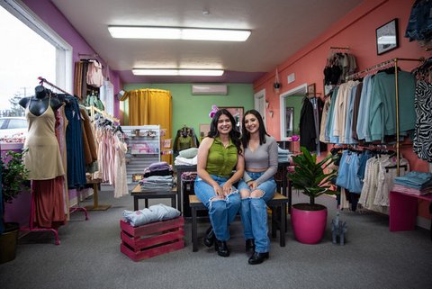 Two young Latinas sitting in their clothing store