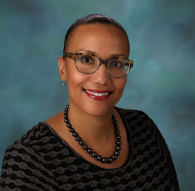 Smiling Black woman wearing glasses and necklace