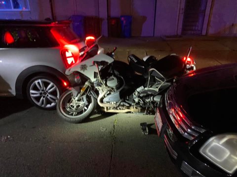 A tipped over police motorcycle and two cars