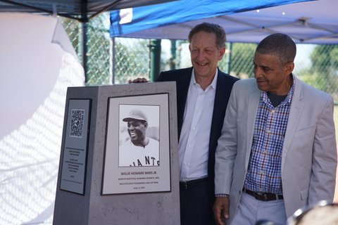 White man and Black man next to a monument with plaque honoring Willie Mays
