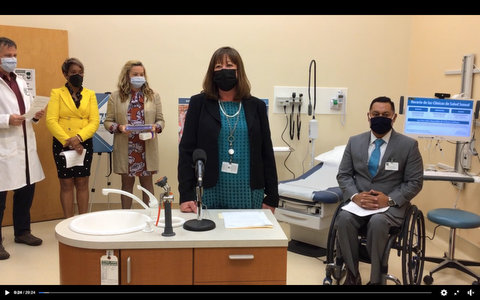 Group of people in medical exam room wearing masks. One is in a wheelchair, and one is in a lab coat.