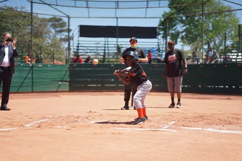 A Black boy at bat with baseball heading toward him