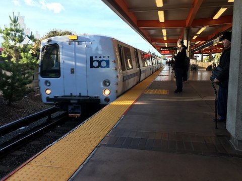 BART train pulling into platform with waiting passengers