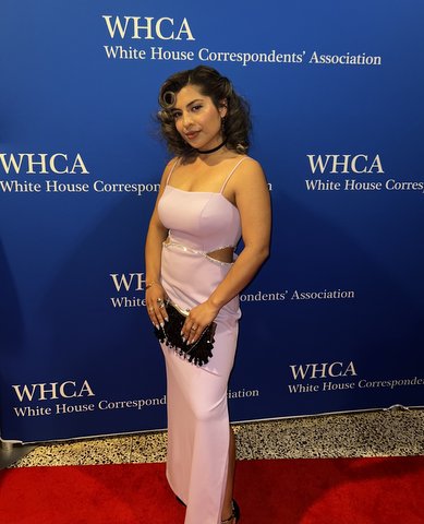 Young Latina on red carpet in front of backdrop that says WHCA White House Correspondents' Association