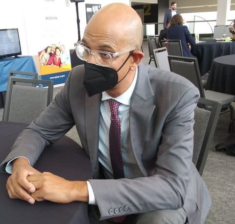A bald man in a suit wearing glasses and a mask