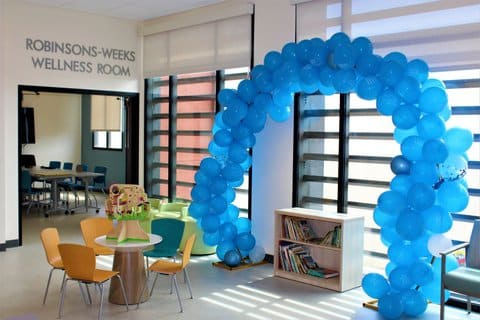 Room decorated with an arch of blue balloons. Lettering over one doorway says Robinsons Weeks Wellness Room.