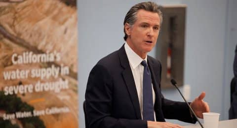 Gov. Gavin Newsom standing at a microphone in front of banner that says "California's water supply in severe drought. Save Water. Save California."