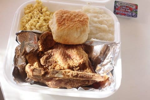 Fried chicken, a biscuit and other food in a to-go container