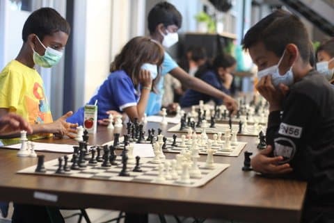Children wearing medical masks playing chess