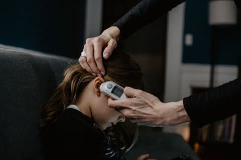 A child having her temperature taken with an ear themometer