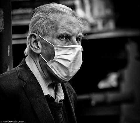 Black-and-white photo of an older white man wearing a white surgical mask
