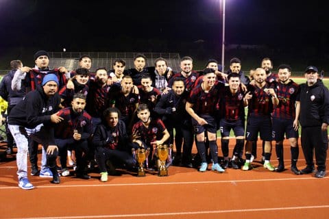 Soccer team posing with two trophies