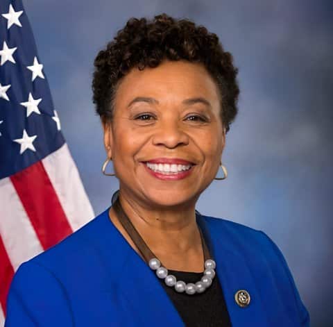 A smiling older Black woman in front of U.S. flag