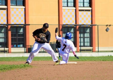 Player slides in feet-first with one leg bent for stolen base in high school baseball game