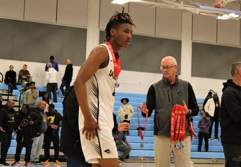 A Black high school basketball player wearing a medal that says CIF stands near an older white man holding more medals