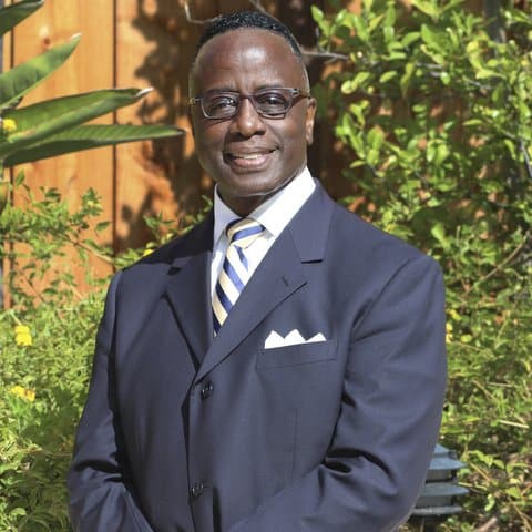 A Black man in a suit posing for a professional photo