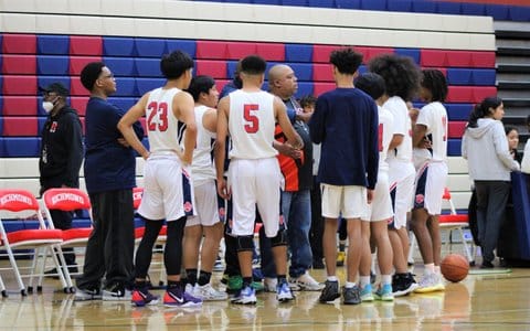A high school boys basketball team huddled on the court
