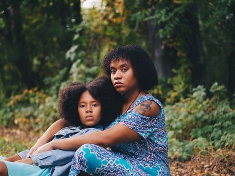 A Black woman and girl sitting together with serious expressions