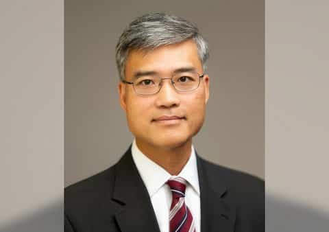 An Asian man with salt-and-pepper hair wearing glasses and a suit and tie.