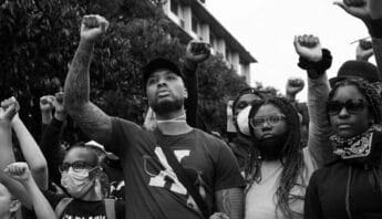 Black-and-white photo of basketball player Damian Lillard and other Black people, each standing with a fist raised in protest.